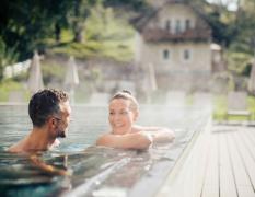 DAS WALCHSEE Sportresort Zwei Gäste im Outdoor-Pool des DAS WALCHSEE Sportresorts