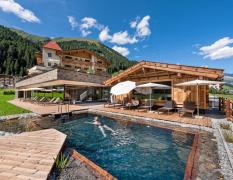 Ansicht des Aussenpools mir Badehaus und dem Alpinhotel berghaus im Hintergrund