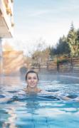 Hotel GUT Trattlerhof und Chalets Eine Dame schwimmt im Aussenpool des Hotels GUT Trattlerhof und Chalets