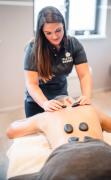 DAS WALCHSEE Sportresort Ein Gast genießt eine Hot-Stone Behandlung durch eine Therapeutim im DAS WALCHSEE Sportresort